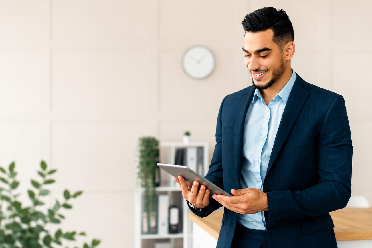 An entrepreneur looks at a tablet, smiling, in a light, calm office